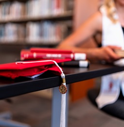 graduation cap and tassel on a table in the library