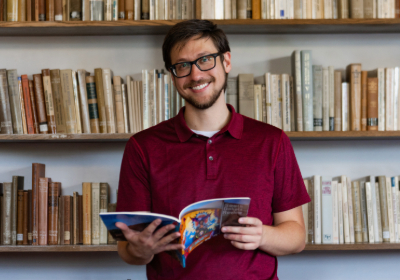 An English student smiling holding a book.