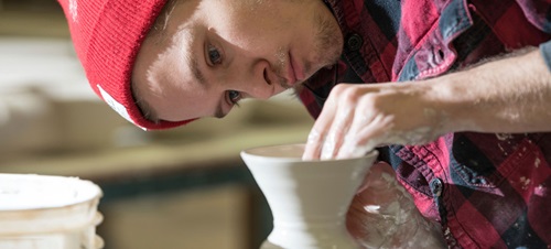 Student working clay on potter's wheel