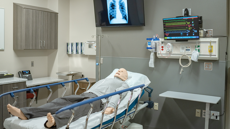 A manikin lays in a hospital bed in a simulation room at the Parry Center.
