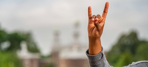 A student holding a Yote hand symbol.