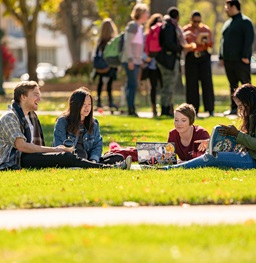 Four students sitting on a blanket studying together n the main campus lawn.