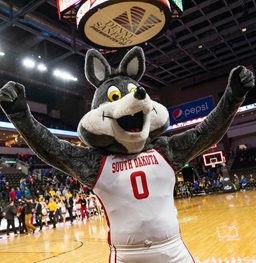 Charlie the Coyote standing arms open on the basketball court.