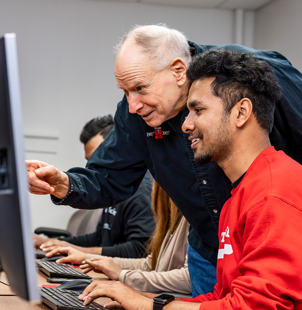 Teacher and student at a computer with a teacher pointing at the screen