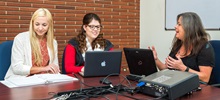 A student and faculty member working on laptops.