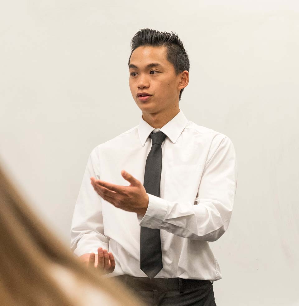 A student in a shirt and tie delivering a presentation.