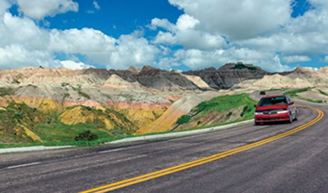 Red van driving on a curving South Dakotan road on a beautiful day