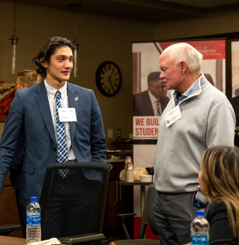 A beacom student talking with a professor at an event.