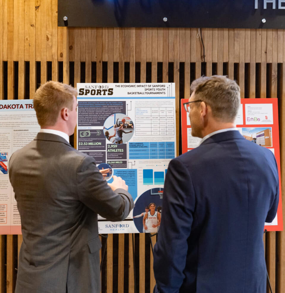 A student presenting research to a man at Coyote Business Consulting's event.