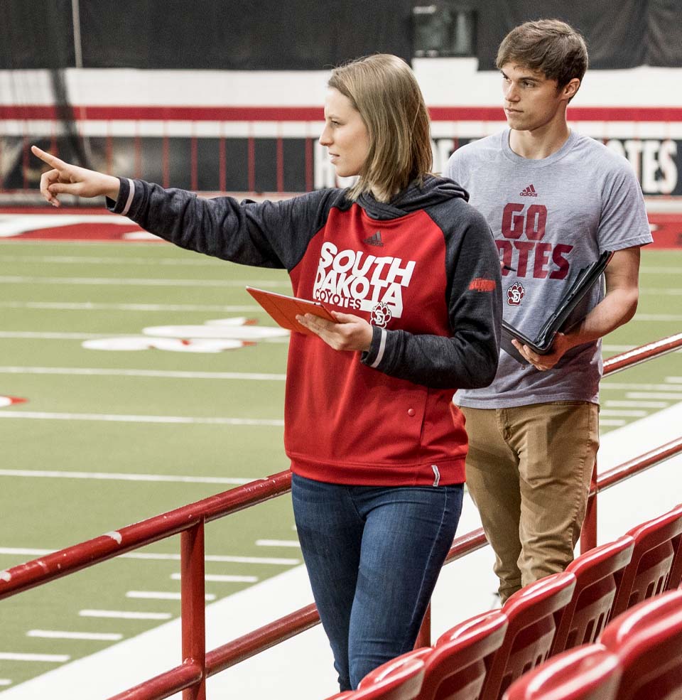 Female and Male Walking Next to Seats in the DakotaDome