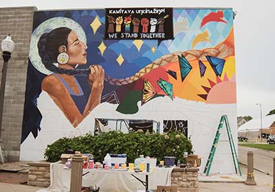 Painting supplies in front of mural painted on building.