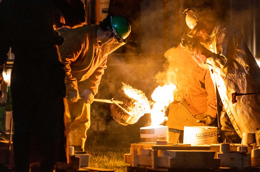 Students pouring metal for art.