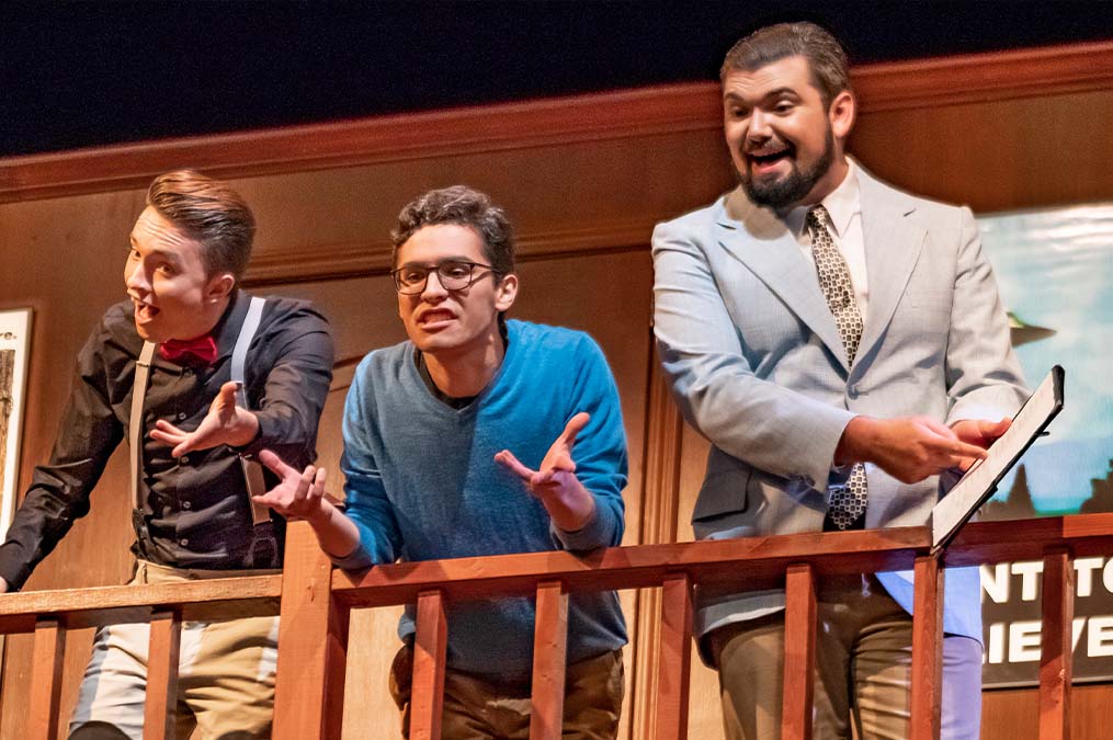 Students performing a play on theatre stage.