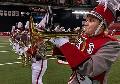 Student playing instrument in the marching band.