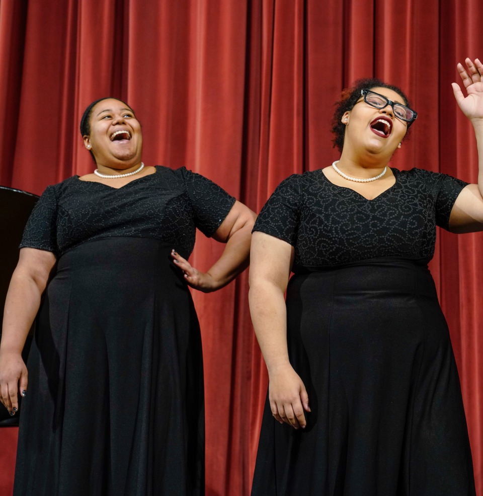 Two USD vocal jazz choir singers on stage.