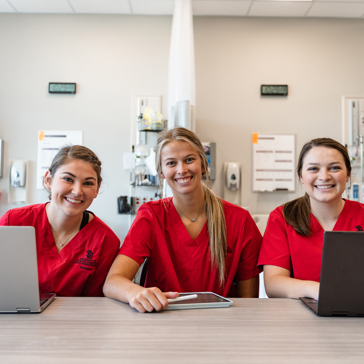 Health sciences students on their laptops smiling.