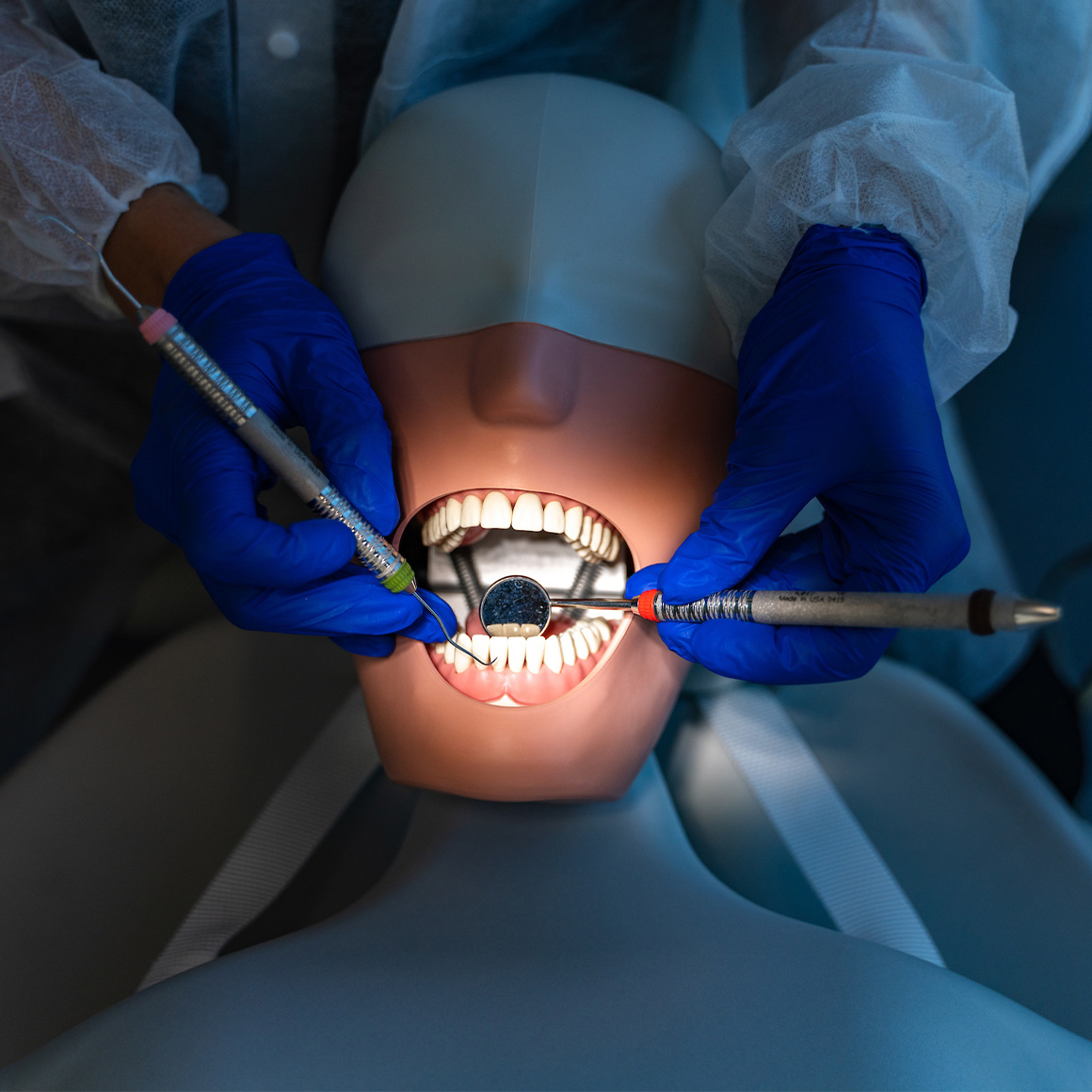 A dental hygienist working on an open mouth.