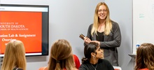 A faculty member teaching students during a presentation.