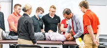 Physical therapy students and their teacher observing a patient in the classroom.