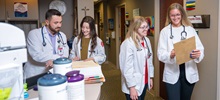 Four Medical students standing and reading documents in their white coats.