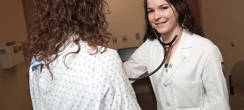 Female in White Lab Coat Listening to Patient's Heart.