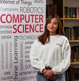 A student posing in front of the computer science robotics sign.