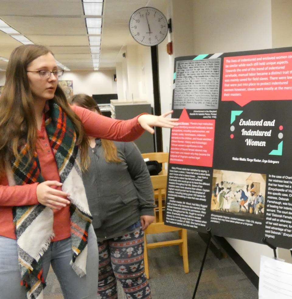 Two students talking about history poster research.
