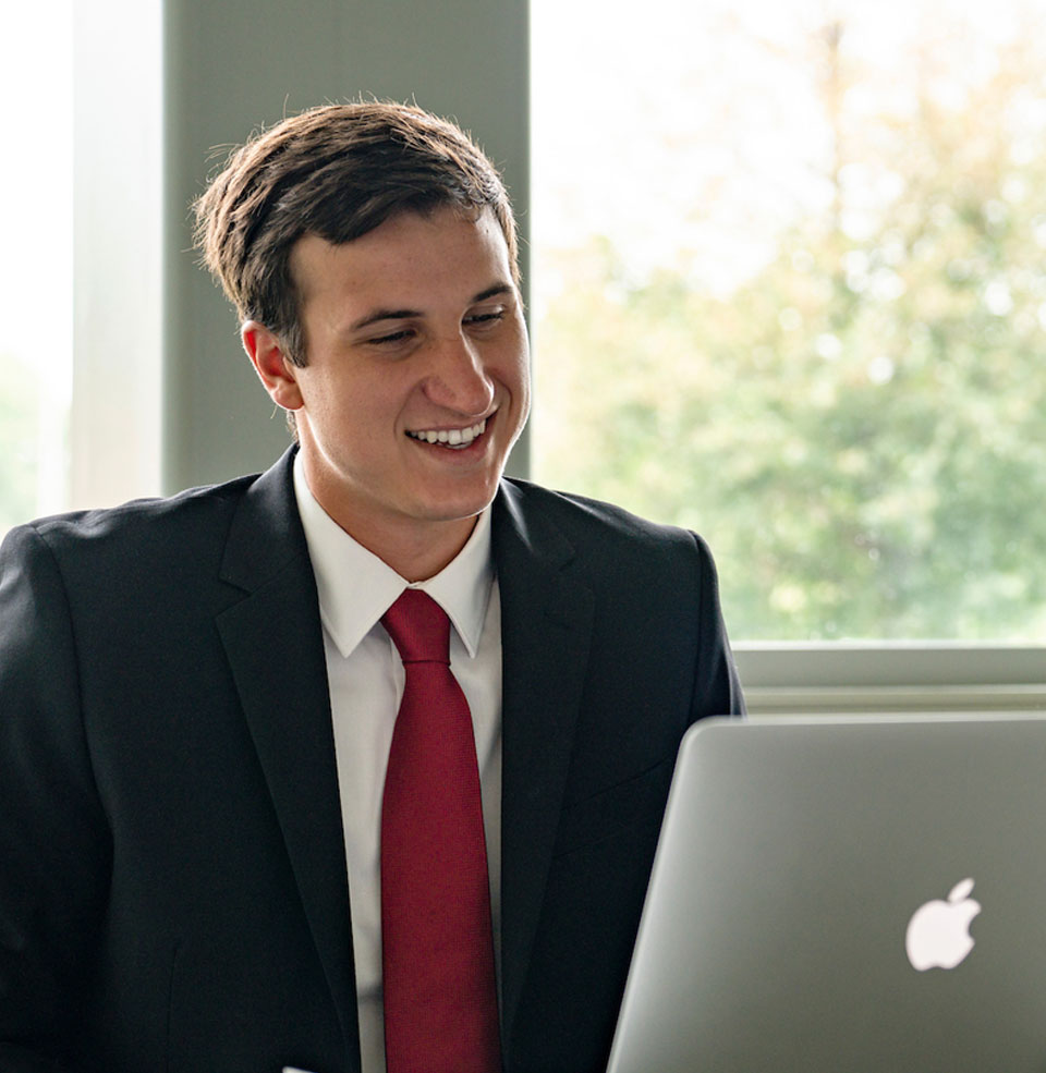 A student on his laptop smiling.