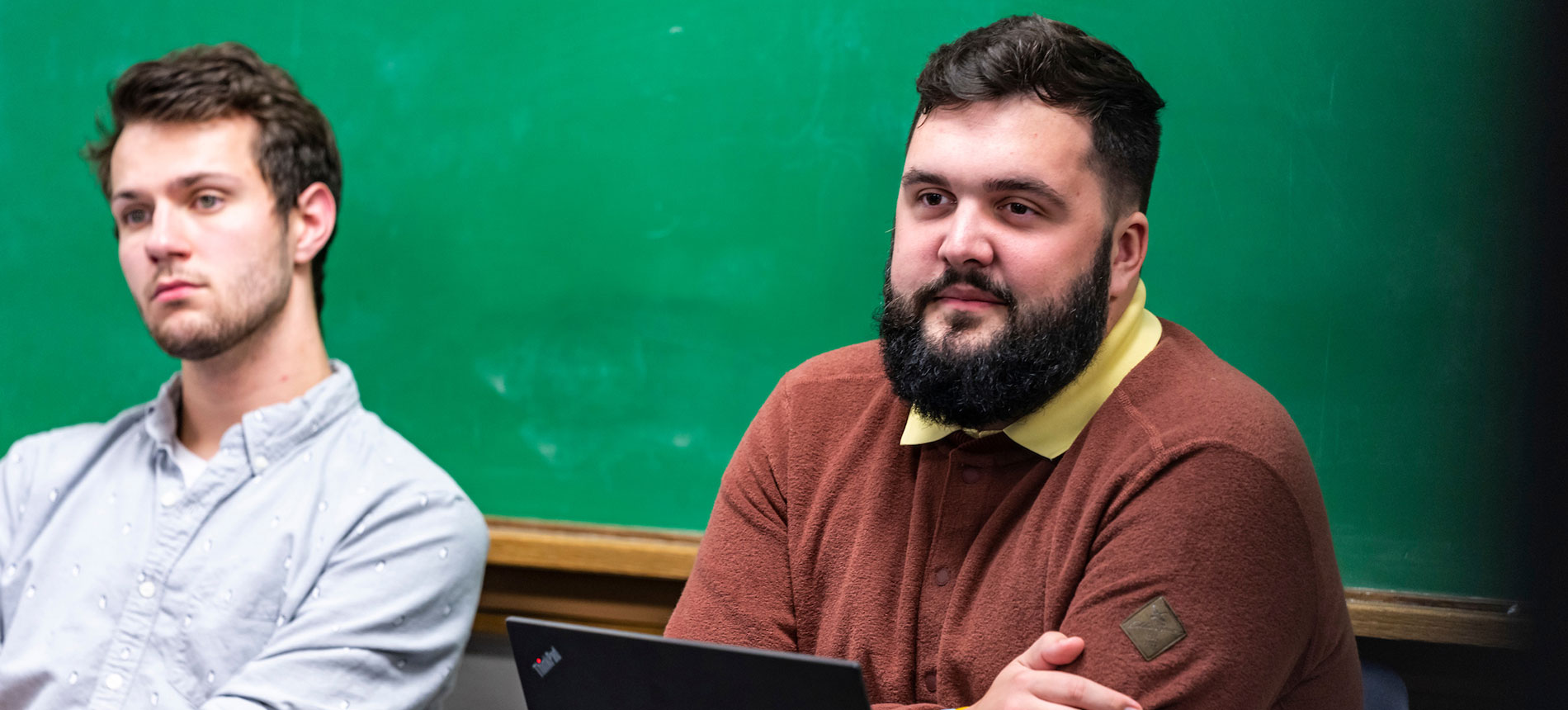 Two students in front of a chalkboard in a classroom.