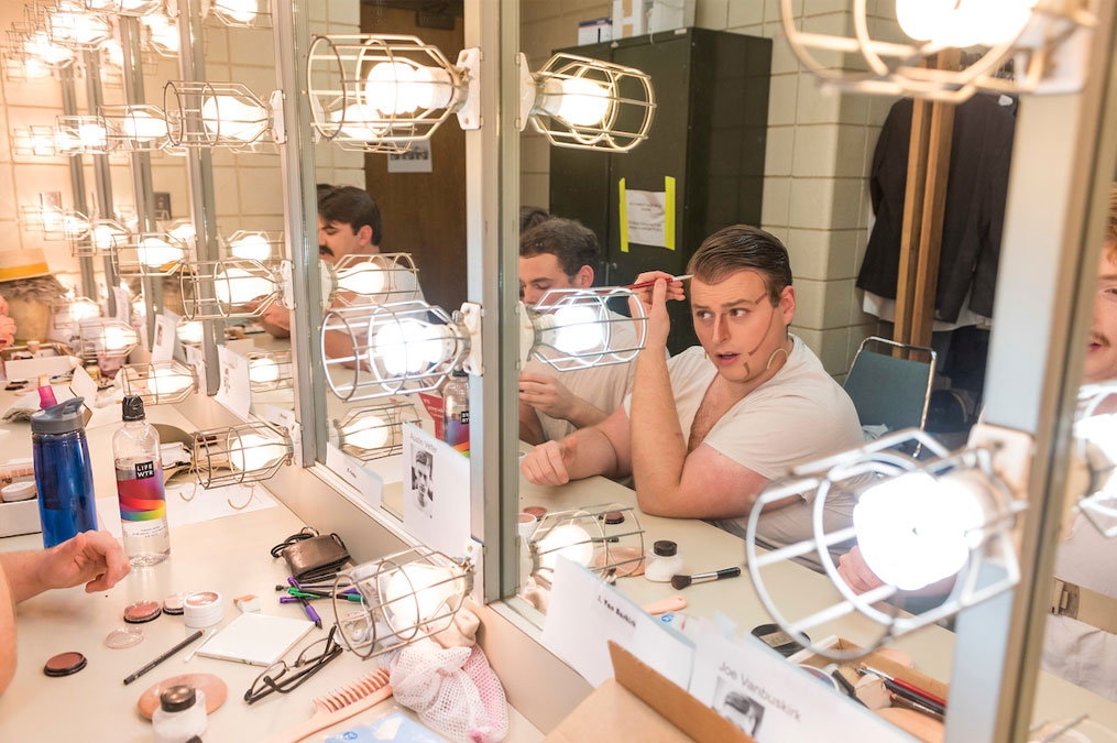 Students applying makeup to prepare for a theatre production