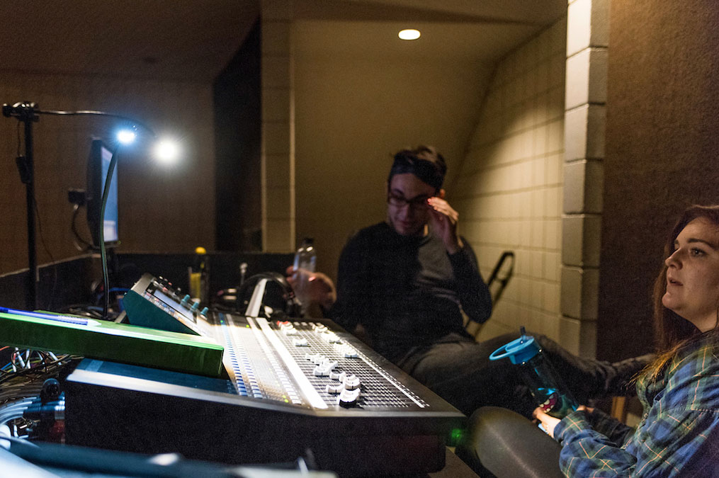 Directors sitting behind the soundboard in the directing booth