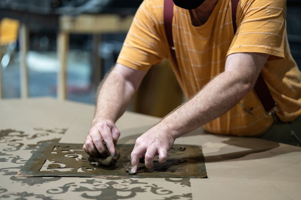 Student using a stencil to paint a large backdrop