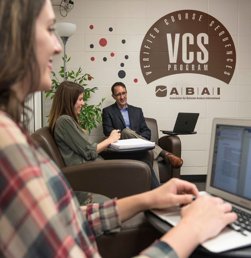 A student typing on her laptop in an office.