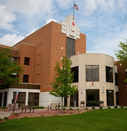 Exterior photo of a hospital, green grass, trees and park benches.