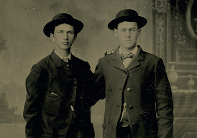 Two men standing together in an old timey photo.
