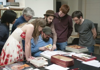 A group of students standing around archival books.