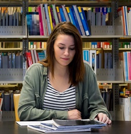 Woman sitting at desk in front of bookshelves looking at photos.