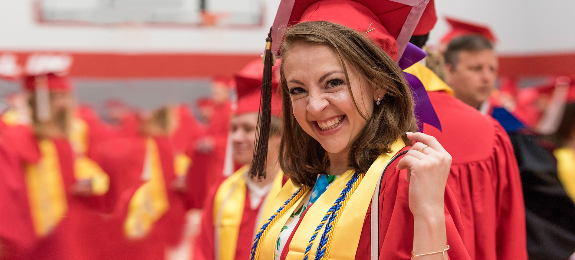 Student at graduation in cap and gown smiling