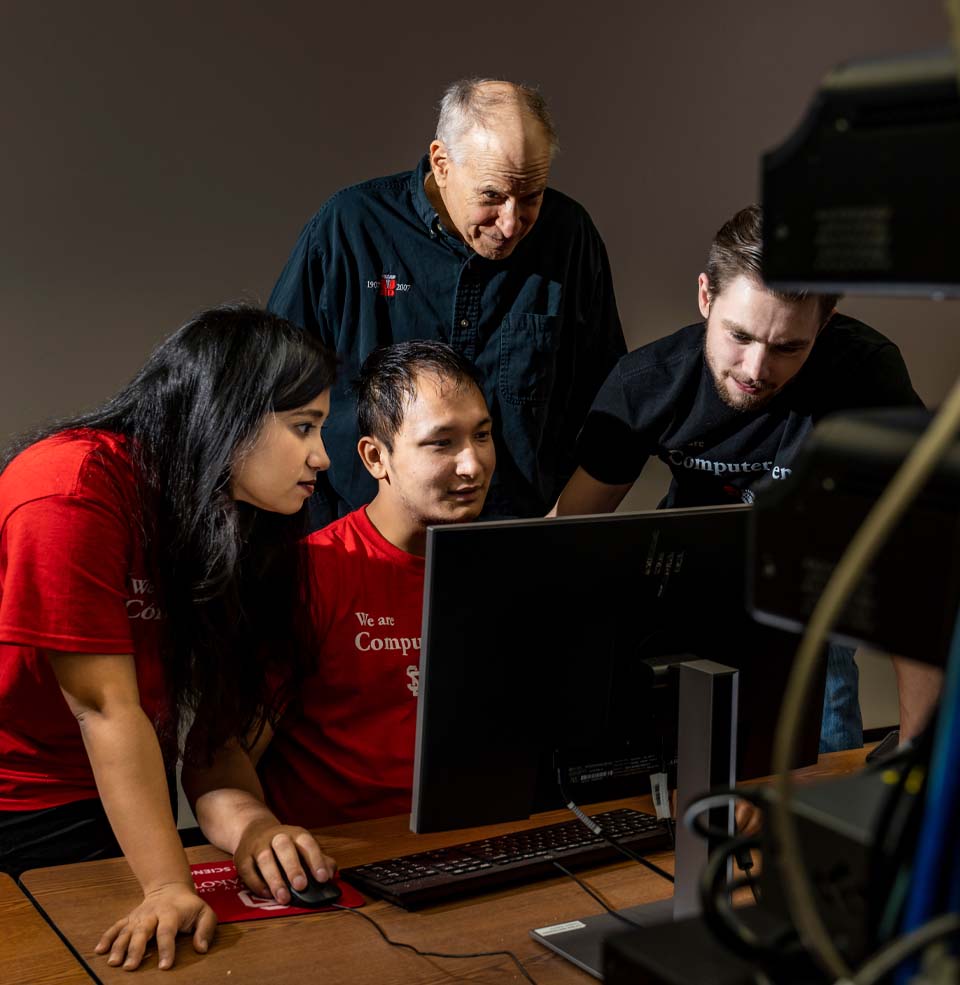 Faculty and students working on a computer