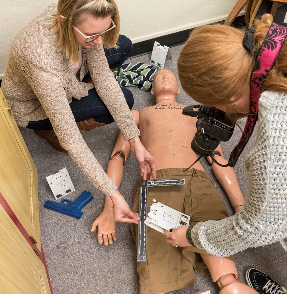 Two female students working moc crime scene dummy victim