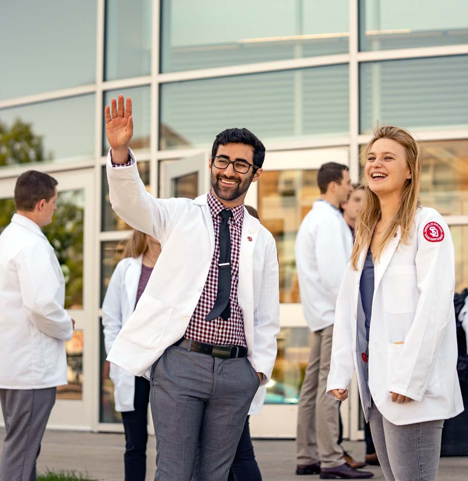 Students waving in front of med school building.