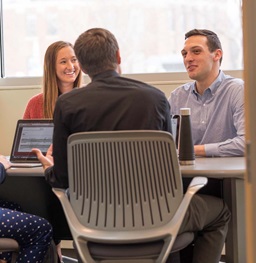 Three students in class talking.