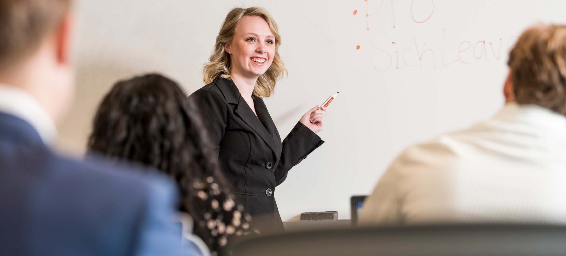 Female in Black Blazer Writing on White Board