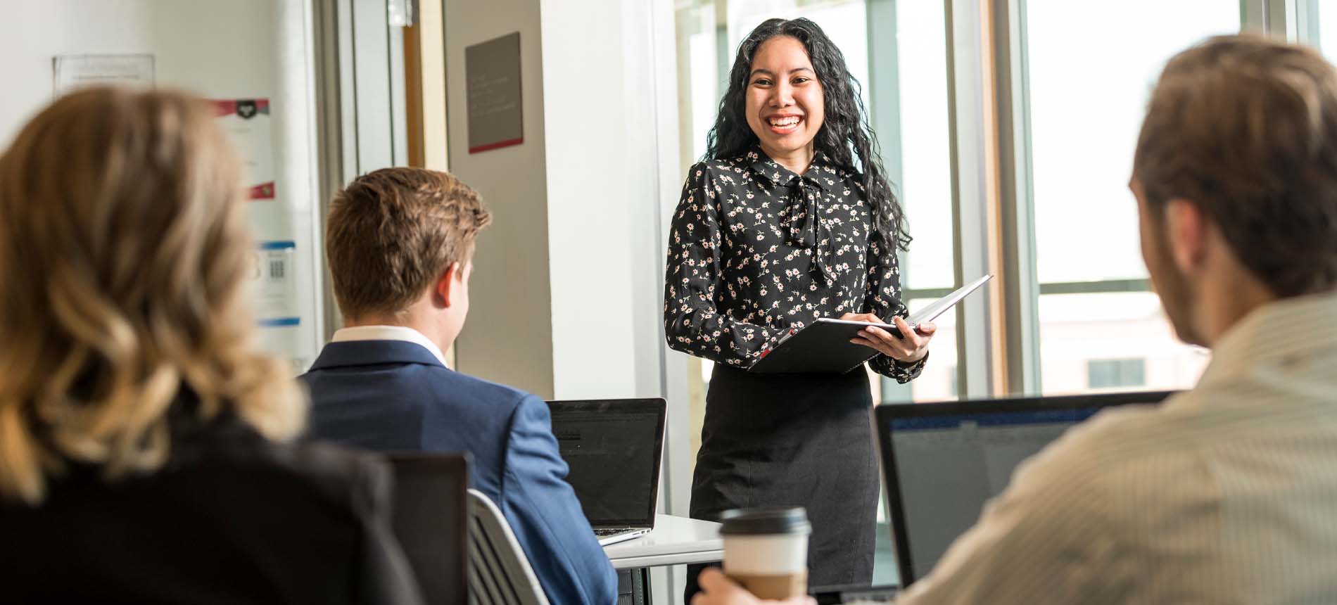 Female in Professional Wear Standing in Front of A Group.