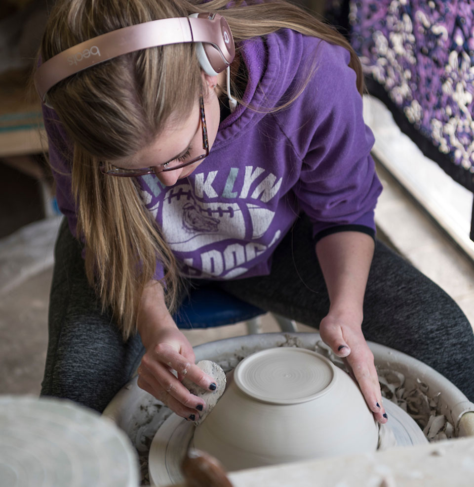 Ceramics student works with clay on the potter's wheel