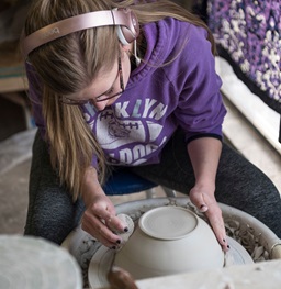 Ceramics student works with clay on the potter's wheel