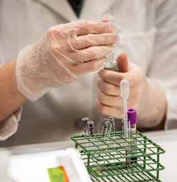 Student holding test tubes and science equipment.