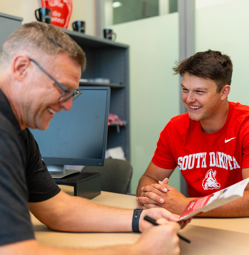 student with professor smiling and looking at a sheet of paper