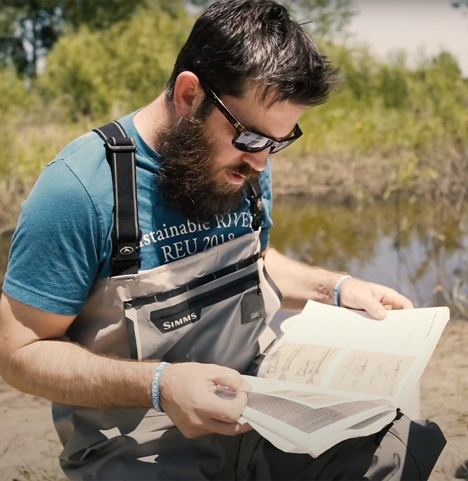 A student doing field research reading a book.