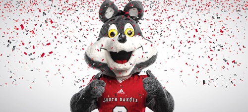 Charlie Coyote smiling and holding two thumbs up with confetti in the background.